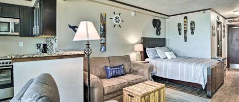 A compact living space with a kitchenette, a sofa, a bed, and a coffee table.