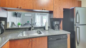 Una cocina moderna con armarios de madera, un lavamanos de acero inoxidable, lavavajillas y refrigerador.