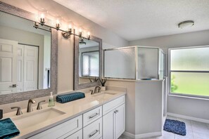 A modern bathroom with a large vanity, a glass shower enclosure, and a large mirror with lights. - Palm Coast Retreat w/ Lanai < 8 Mi to Beach! (Palm Coast)