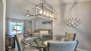 Ett modernt matområde med ett glasbord och stolar, en takfläkt och en väggmonterad lampa.