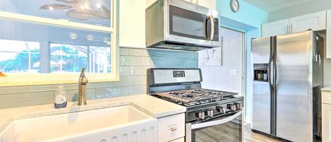 Una cucina moderna con piano cottura a gas, forno a microonde, forno e frigorifero in acciaio inossidabile.