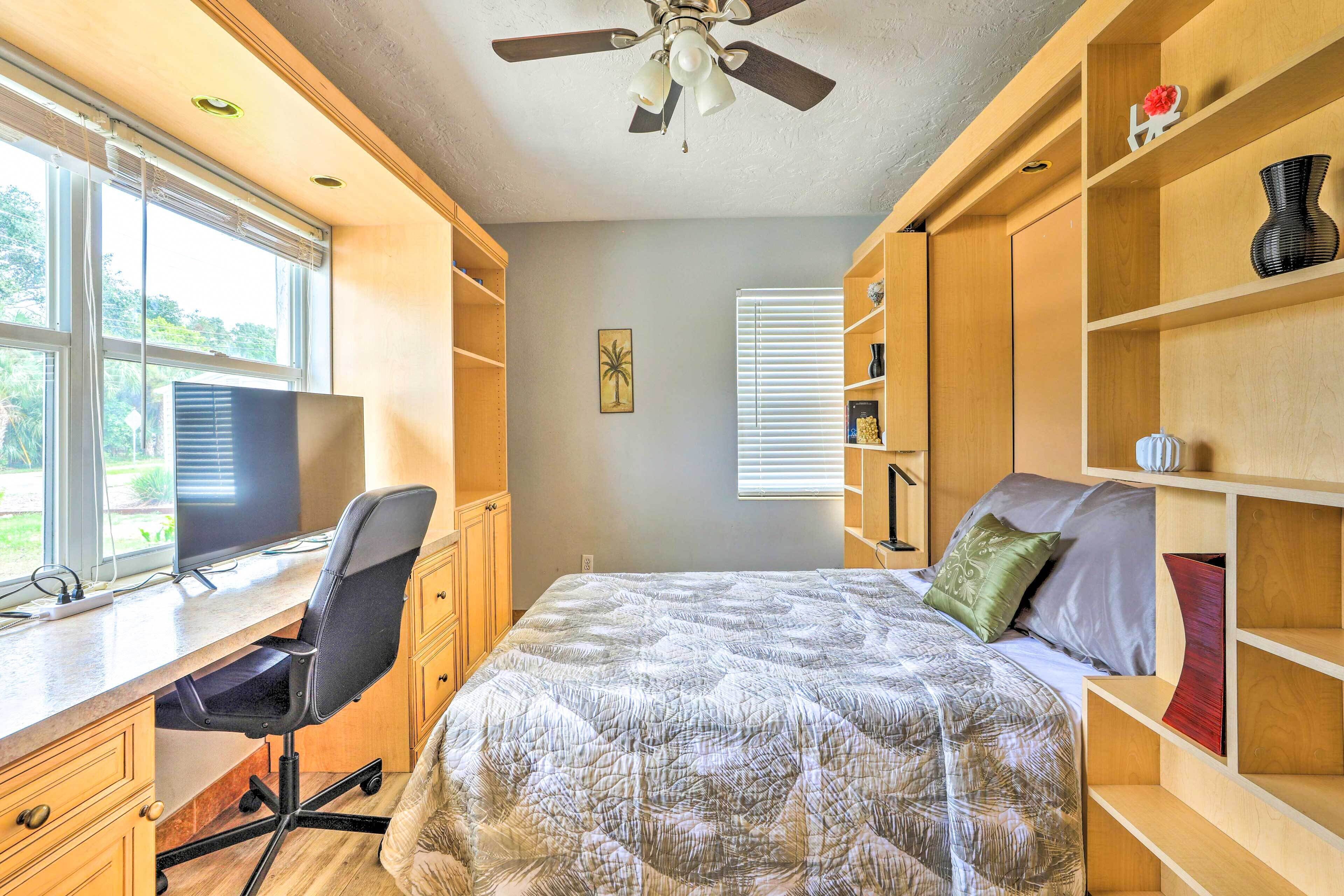 Une chambre à coucher comprenant un bureau, un ordinateur, un lit et des étagères.