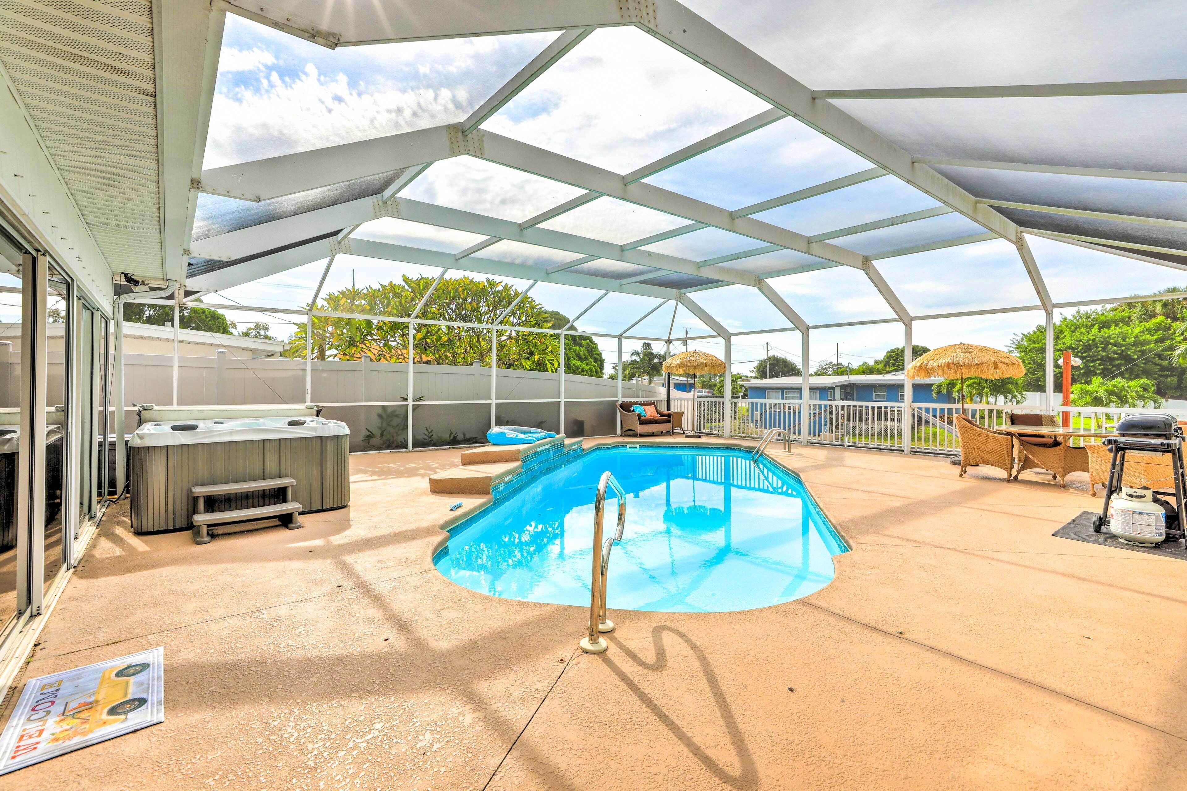 En udendørs swimmingpool med et overdækket område, jacuzzi og udendørs møbler.