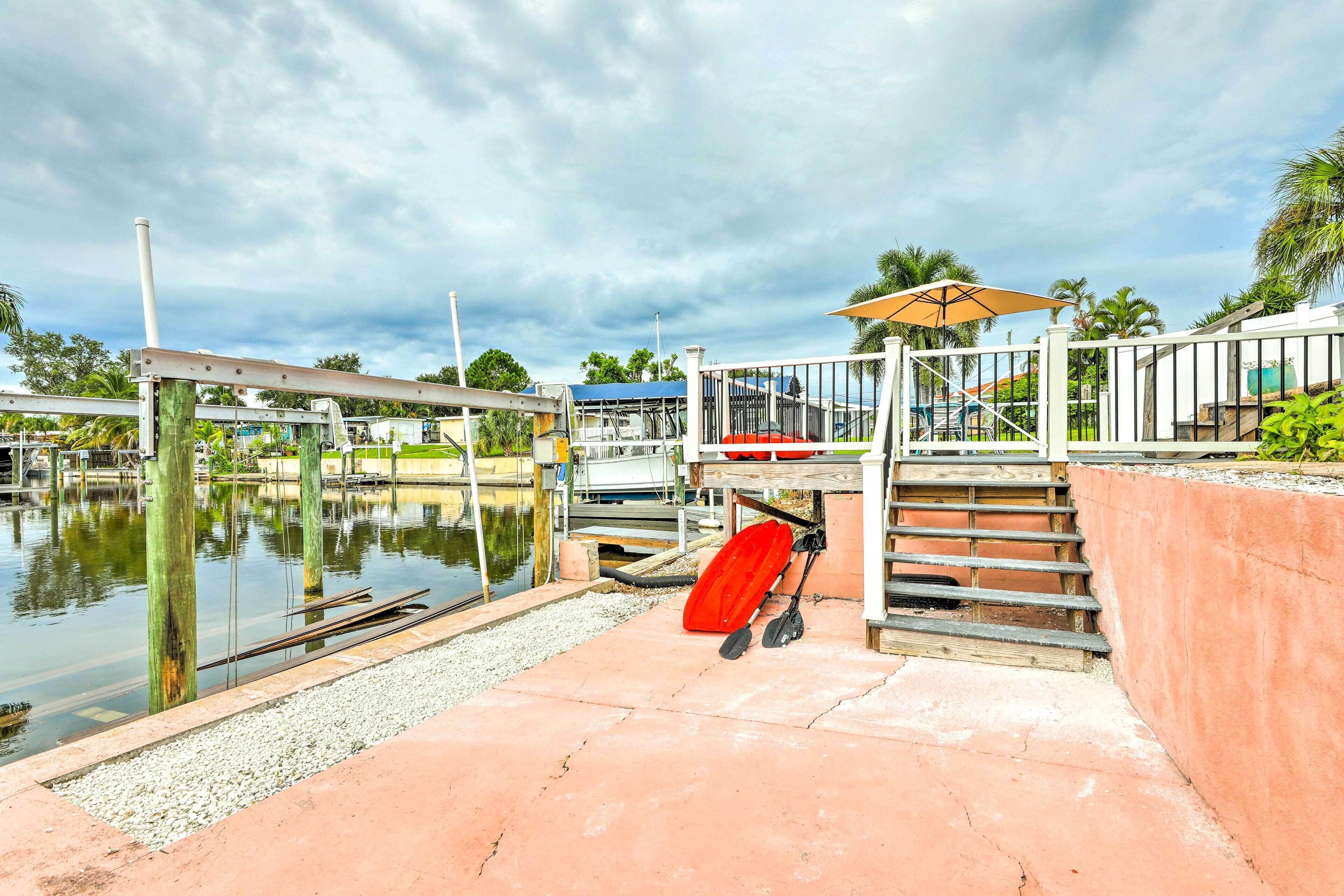 A dock area with a boat ramp, a red paddleboard, and a covered seating area with a table and chairs.