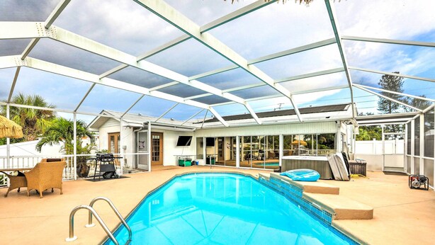 An indoor swimming pool with a glass ceiling, surrounded by lounge chairs and a barbecue area. - 'ocean Breeze Oasis' w/ Boat Dock & Slip on Canal! (Bradenton)