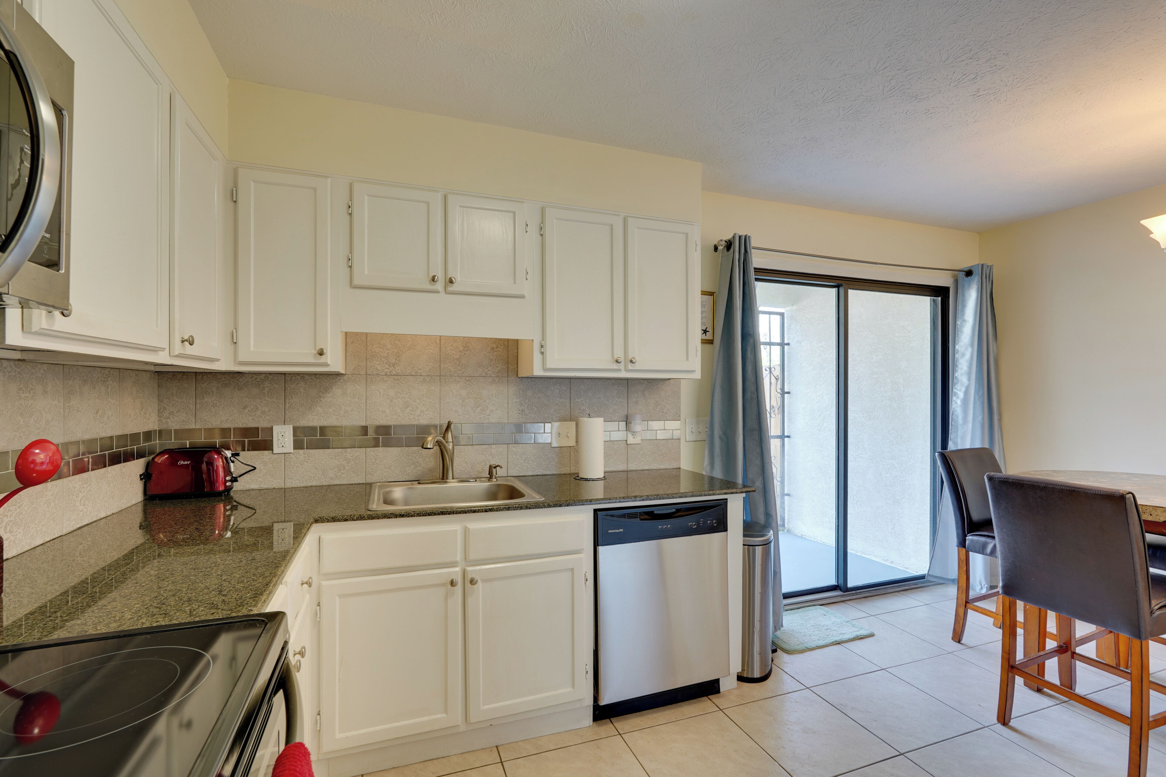 A modern kitchen with white cabinets, a dishwasher, and a red toaster.