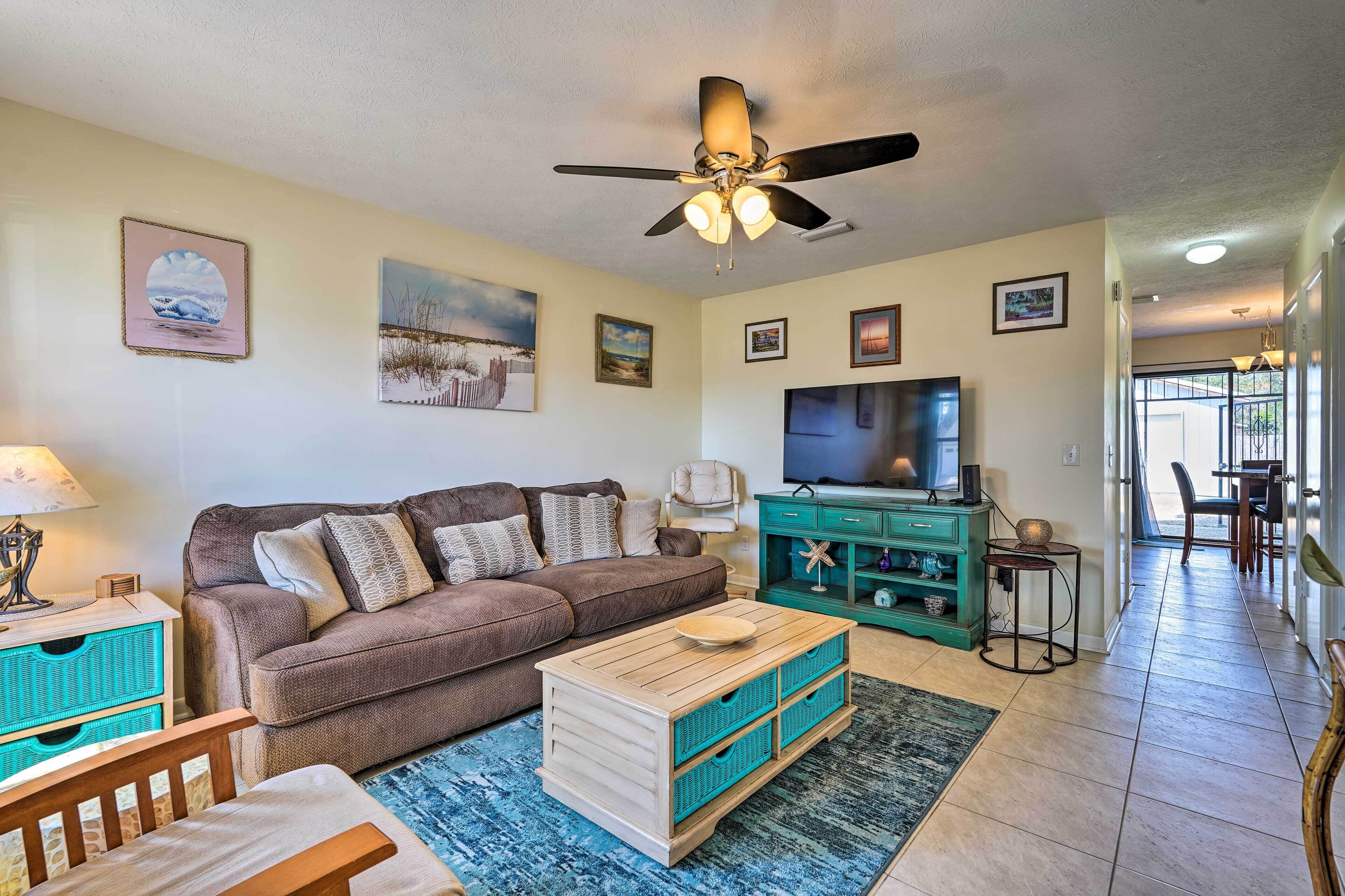 A living room with a brown sofa, wooden coffee table, teal storage unit, and a ceiling fan.