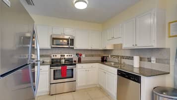A modern kitchen with white cabinets, stainless steel appliances, and a tiled backsplash.