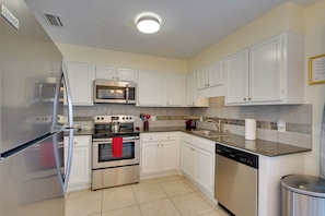 A modern kitchen with white cabinets, stainless steel appliances, and a tiled backsplash. - Panama City Townhome w/ Balcony, Water Views! (Panama City)