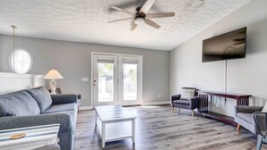A spacious living room with a grey sofa, a white coffee table, and a ceiling fan. - Private Pool & Hot Tub at Panama City Home! (Panama City Beach)