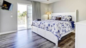 A bedroom with a bed, a ceiling fan, a TV mounted on the wall, and a door leading to an outdoor area. - Private Pool & Hot Tub at Panama City Home! (Panama City Beach)