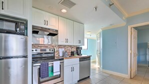 A modern kitchen with stainless steel appliances, white cabinetry, and a tiled backsplash.