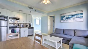 A modern kitchen with white cabinets, stainless steel appliances, and a dining area with a wooden table and chairs.