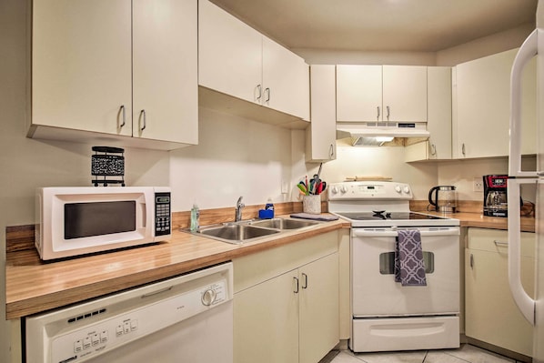 A compact kitchen with white cabinets, a microwave, a stove, and a dishwasher.