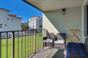 A balcony with outdoor furniture, a view of neighboring buildings, and a clear sky. - Ocean Views + Pool Access: Tierra Verde Condo! (Tierra Verde)