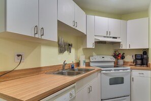 A kitchen with white cabinets, a wooden countertop, a GE stove, a coffee maker, and a sink. - Ocean Views + Pool Access: Tierra Verde Condo! (Tierra Verde)