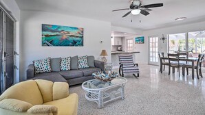 A spacious living area with a sofa, armchair, and dining table. - Palm City Canalfront Home w/ Boat Dock & Fire Pit! (Palm City)