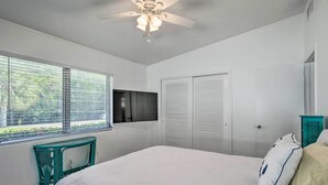 A bedroom with a bed, a ceiling fan, a window with blinds, a TV mounted on the wall, and a closet with sliding doors. - Palm City Canalfront Home w/ Boat Dock & Fire Pit! (Palm City)