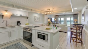 Uma cozinha moderna com armários brancos, uma ilha central e uma área de refeições com mesa redonda e cadeiras.