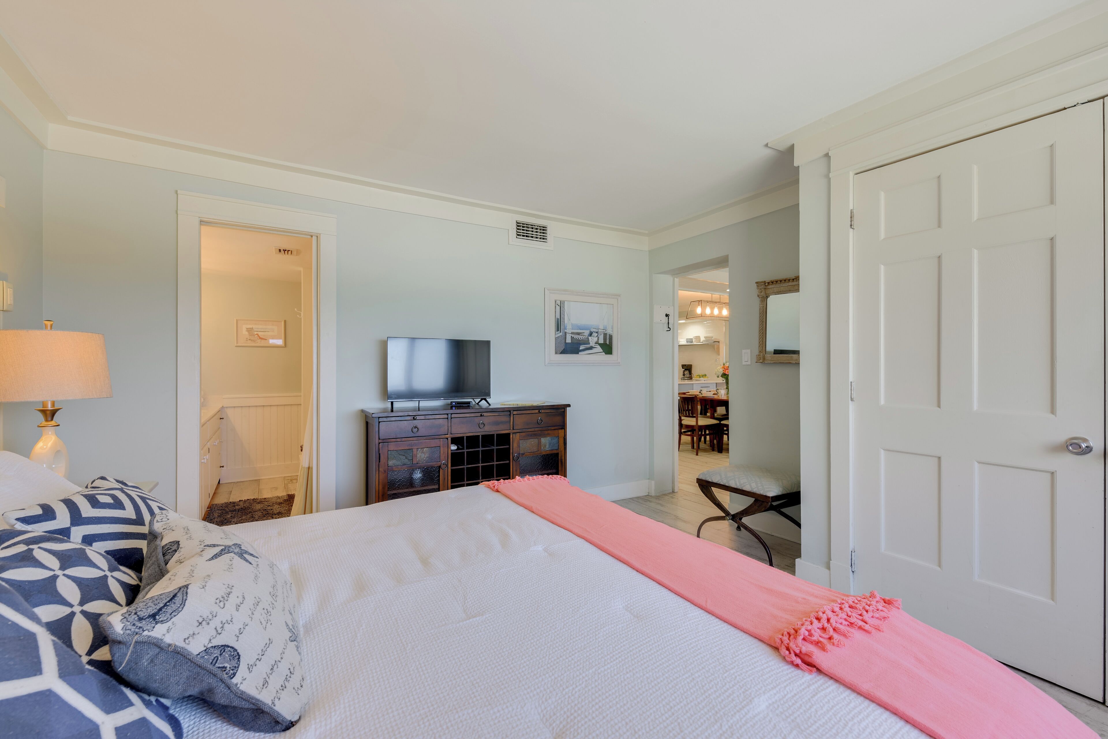 Habitació d'hotel amb un llit, una televisió, un taulell i una porta que dóna a una altra habitació.