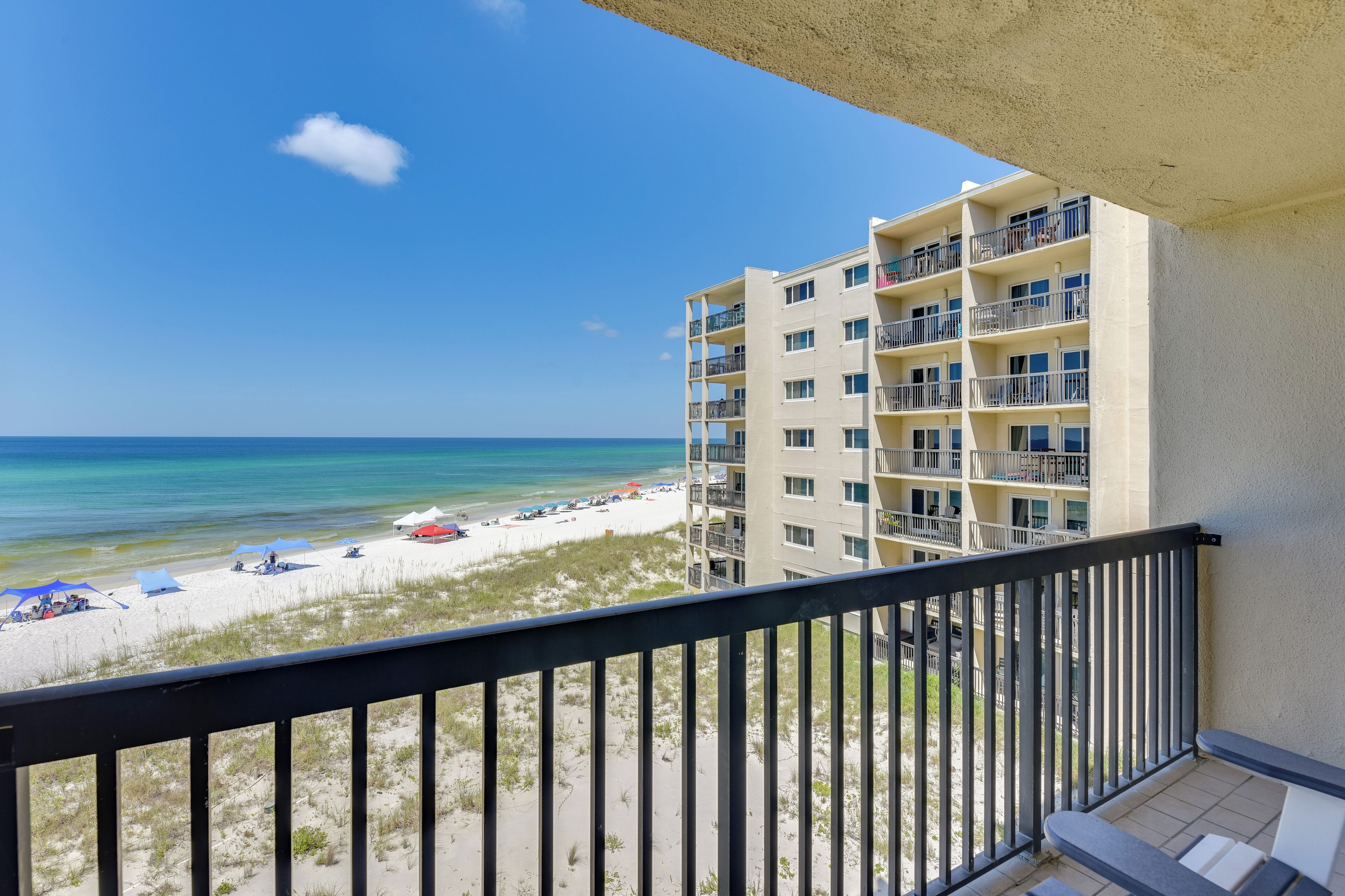 A balcony with a view of a beach and a multi-story building.