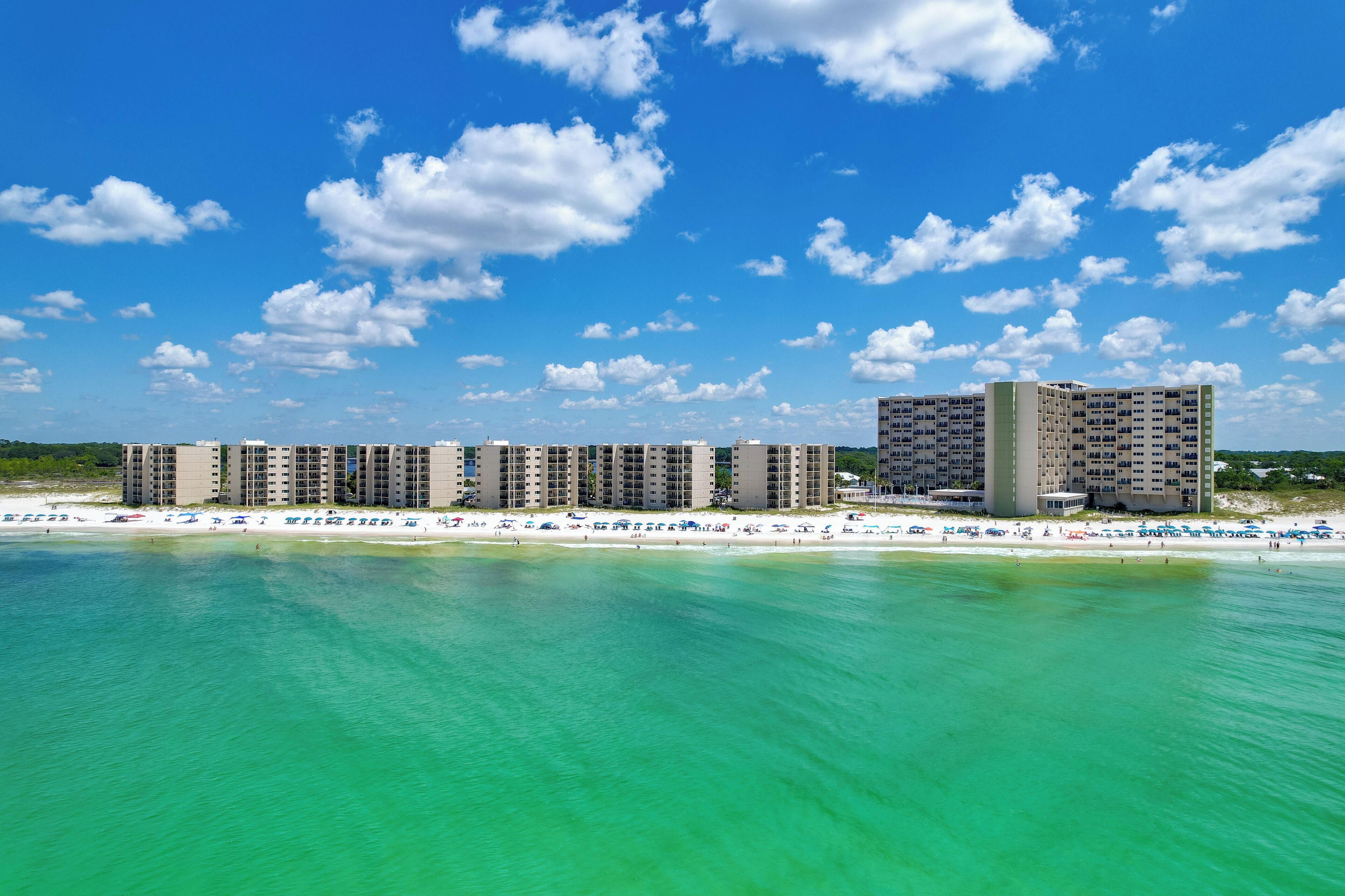 A beachfront hotel with multiple high-rise buildings, a sandy beach, and clear turquoise waters.