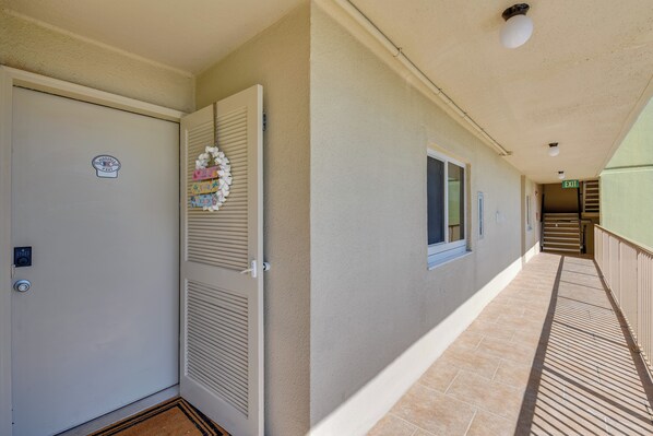 A hotel corridor with a closed door, a security keypad, and a doormat.