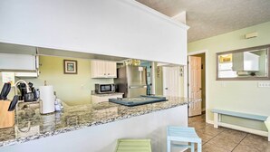 A kitchen with granite countertops, stainless steel appliances, and a small island with stools.
