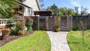 Ein Garten mit Holzzaun, Pflasterweg und einer Pergola.