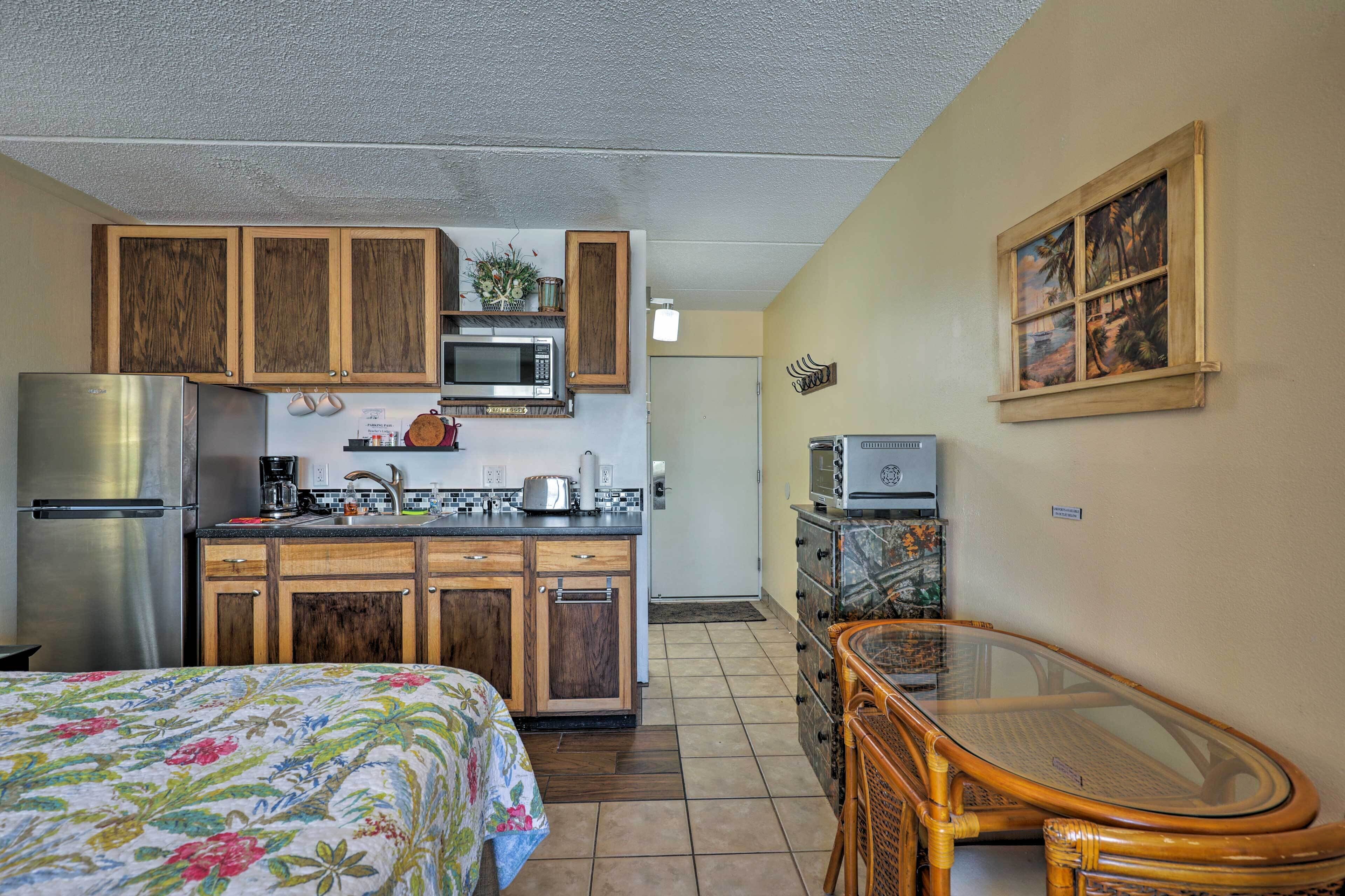 A compact kitchen with wooden cabinets, a microwave, and a toaster.