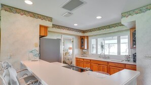 A kitchen with a central island, wooden cabinets, and a window providing natural light. - Cozy Frostproof Escape w/ Private Hot Tub! (Frostproof)