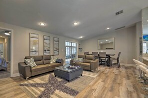 Uma sala de estar ampla com um sofá grande, uma mesa de centro e um espaço de jantar com mesa e cadeiras.