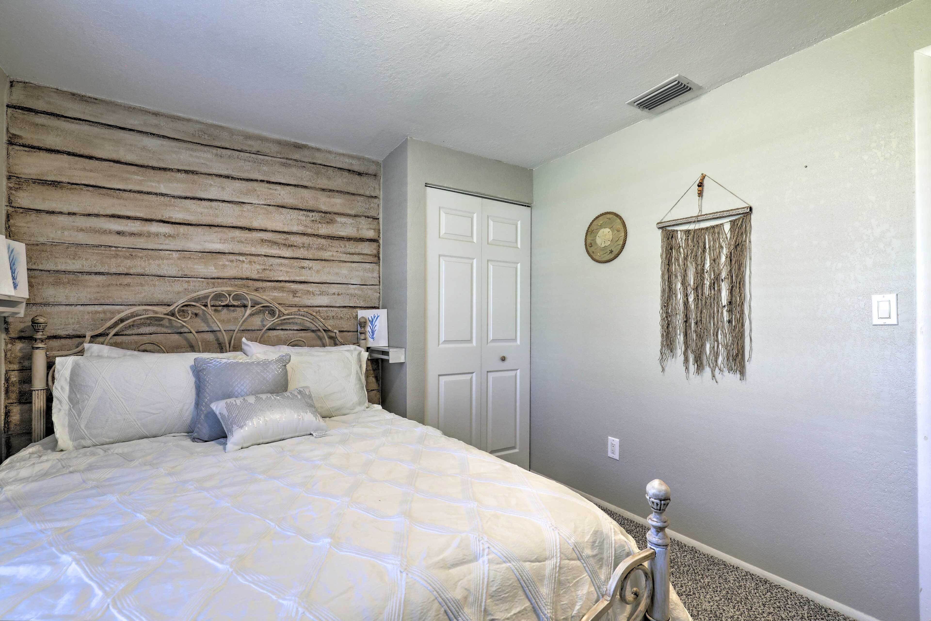 Une chambre à coucher avec un lit, une tête de lit en bois, une porte blanche et une décoration murale.