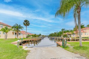 A canal with wooden docks and boats, surrounded by palm trees and buildings with red roofs. - Resort Perks: Family Gem w/ Homosassa River Access (Homosassa)