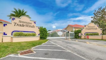 A gated entrance to Homosassa Trade Winds with a clear sky and palm trees.