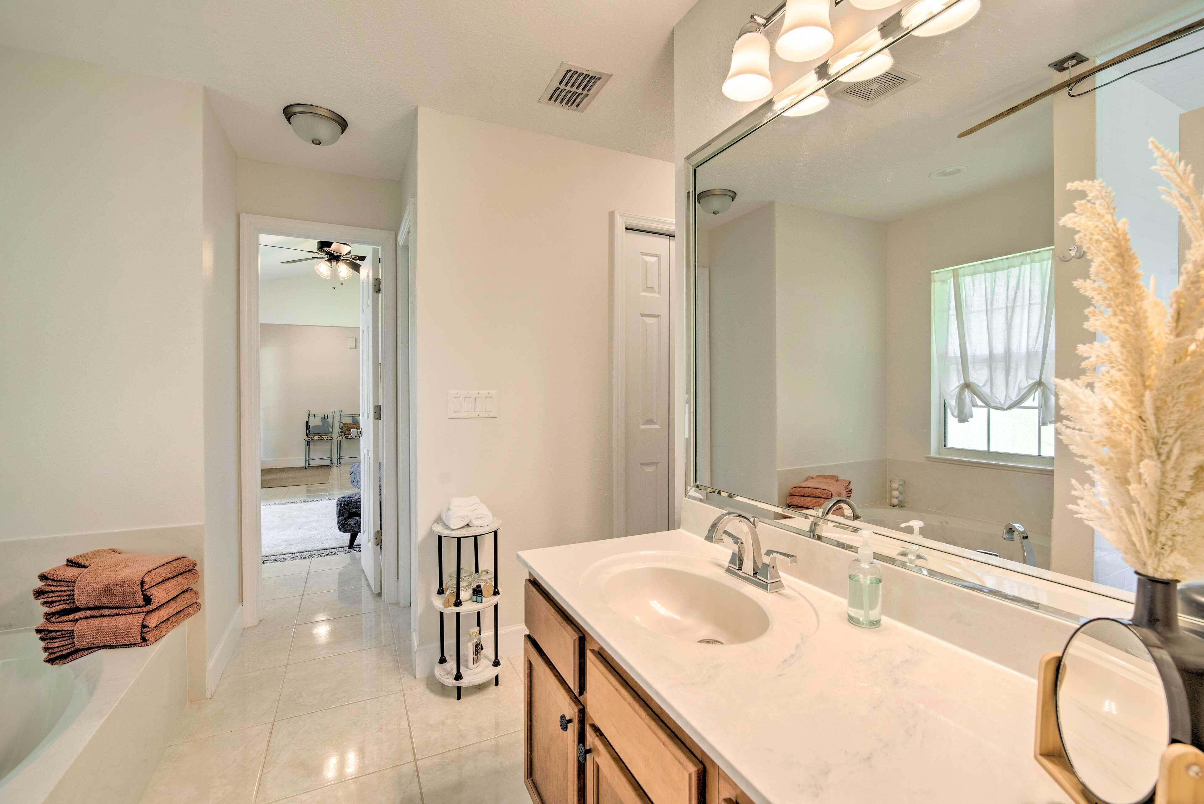 Une salle de bain avec un grand miroir, un lavabo et un porte-serviettes.