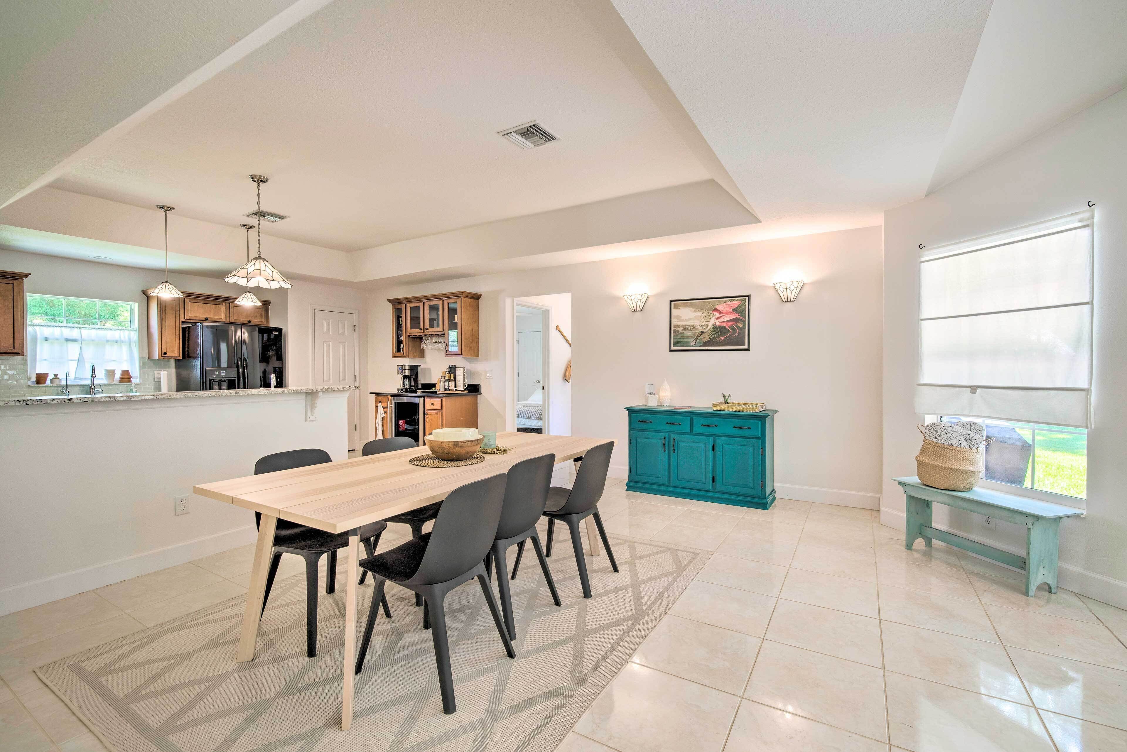 Une cuisine moderne avec un coin repas, comprenant une table en bois, des chaises noires et des meubles de couleur turquoise.
