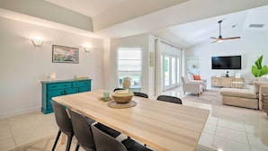 A spacious living area with a wooden dining table, teal cabinetry, and a large TV. - Private Pool & Grill: Peaceful Home in Dunnellon (Dunnellon)