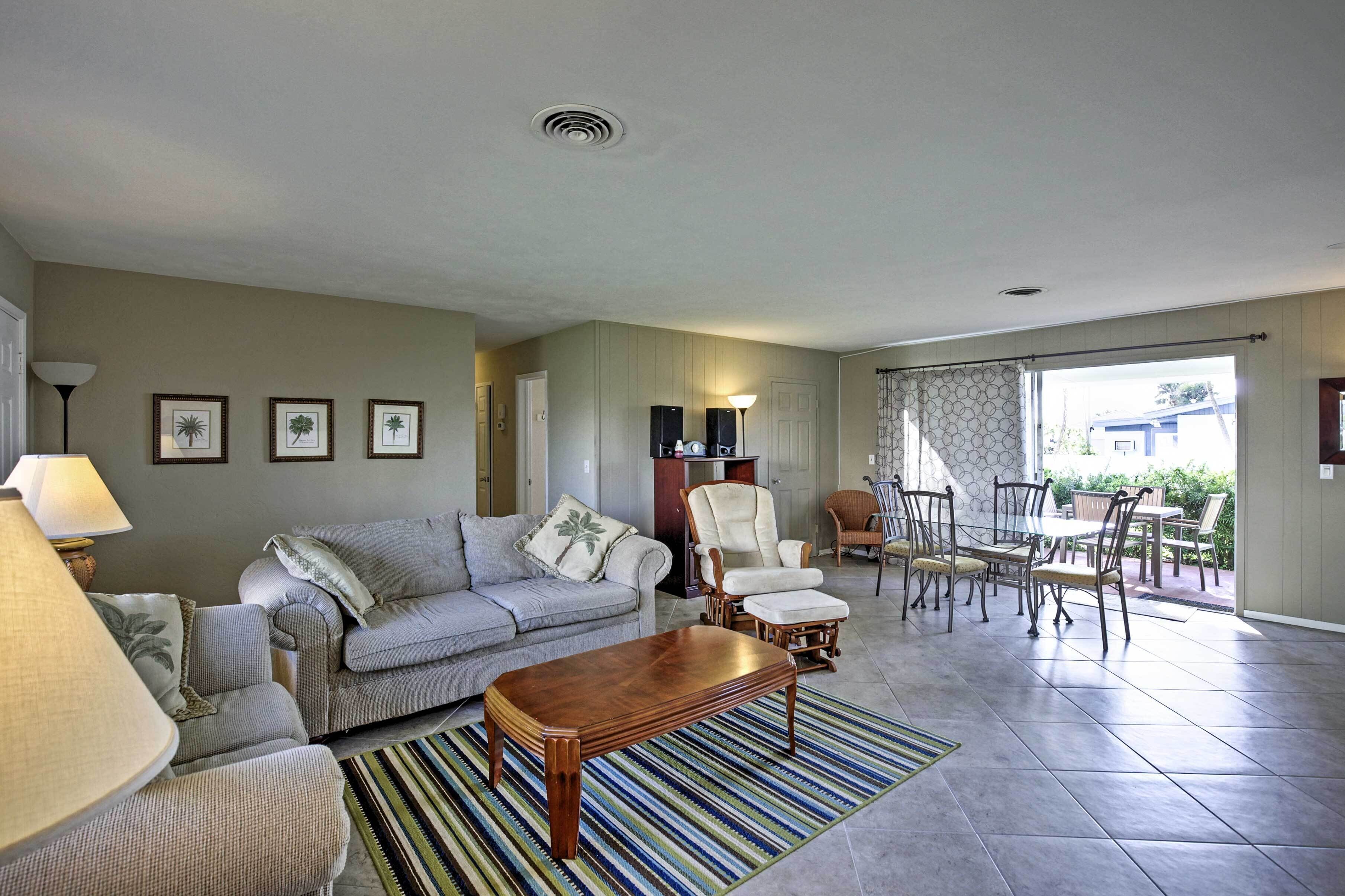 A living room with a sofa, armchairs, a coffee table, and a dining area with chairs and a table.