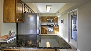 A kitchen with wooden cabinets, a stainless steel refrigerator, a microwave, and an oven. - Pet-friendly Daytona Beach Home, Walk to the Ocean (Port Orange)
