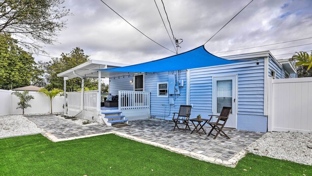 A blue house with a covered patio, a white fence, and a lawn. - Family-friendly Gulfport Retreat Near the Beach (Gulfport)