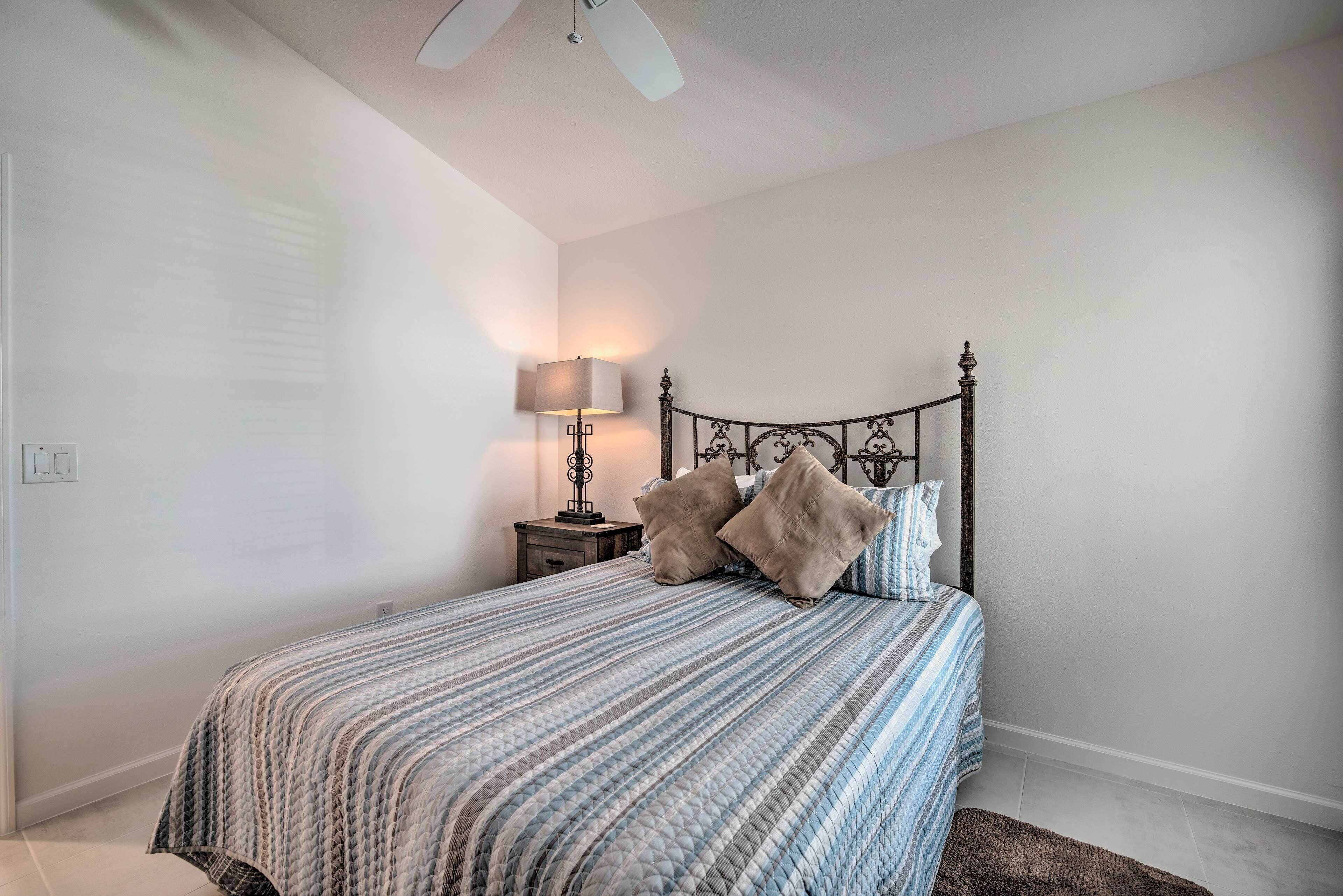 A bedroom with a bed, a nightstand, a lamp, and a ceiling fan.