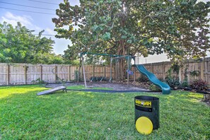 A backyard with a swing set, a slide, a tree, and a trash can. - Pet-friendly Home w/ Pool < 4 Mi to Beach! (Deerfield Beach)