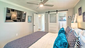 A bedroom with a bed, a ceiling fan, and a door leading to a bathroom. - Punta Gorda Retreat Near Historic Downtown! (Punta Gorda)