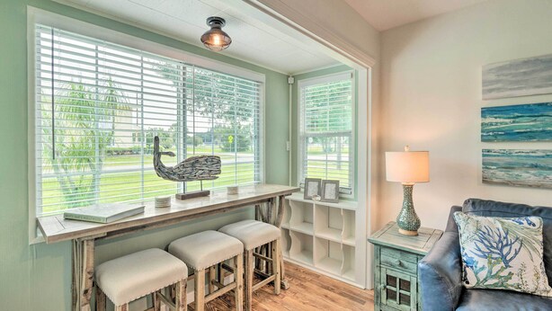 A room with a wooden bench with cushioned seats, a small table with a lamp, and a wall-mounted shelf. - Punta Gorda Retreat Near Historic Downtown! (Punta Gorda)