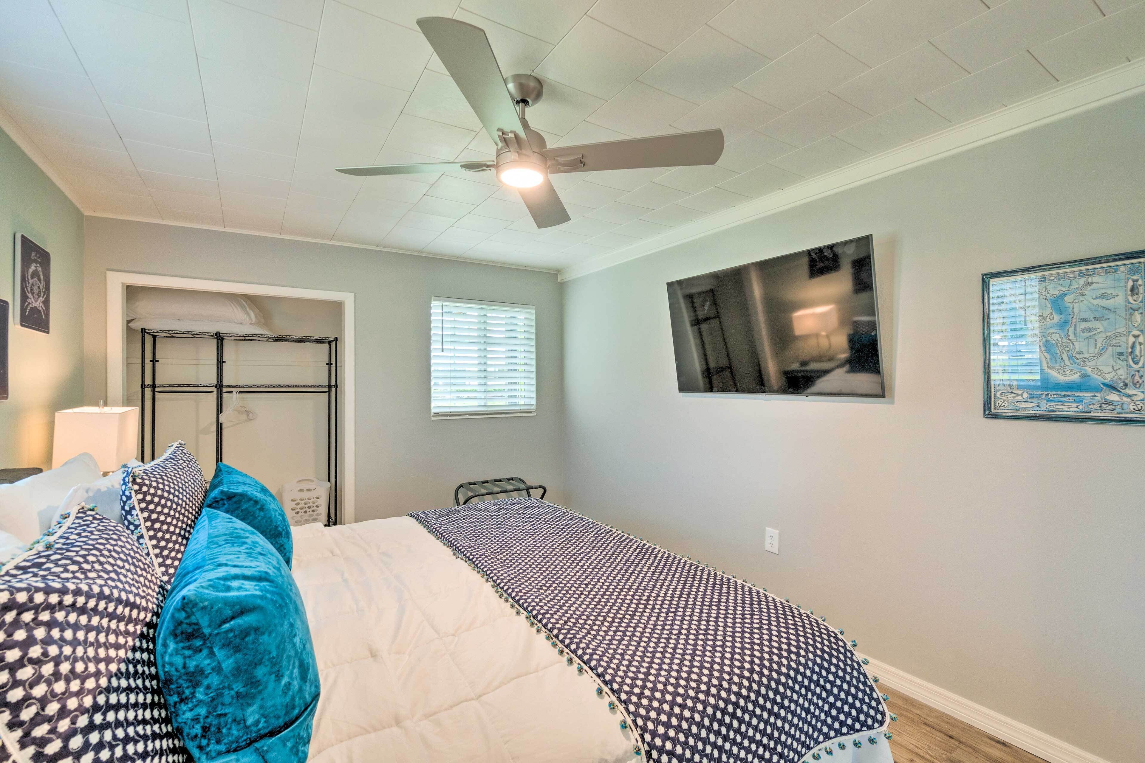 Une chambre à coucher avec un lit, un ventilateur de plafond, une fenêtre et un tableau accroché au mur.