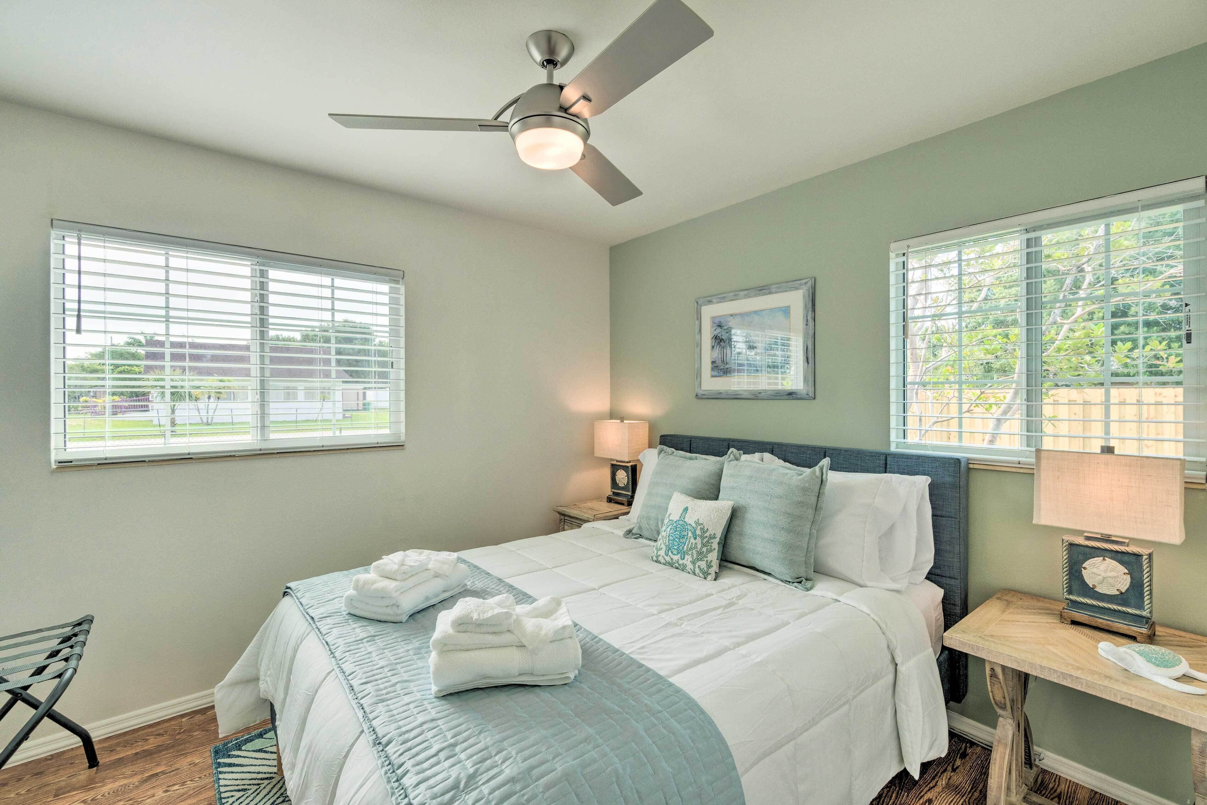 A bedroom with a bed, a nightstand, a chair, and a ceiling fan.