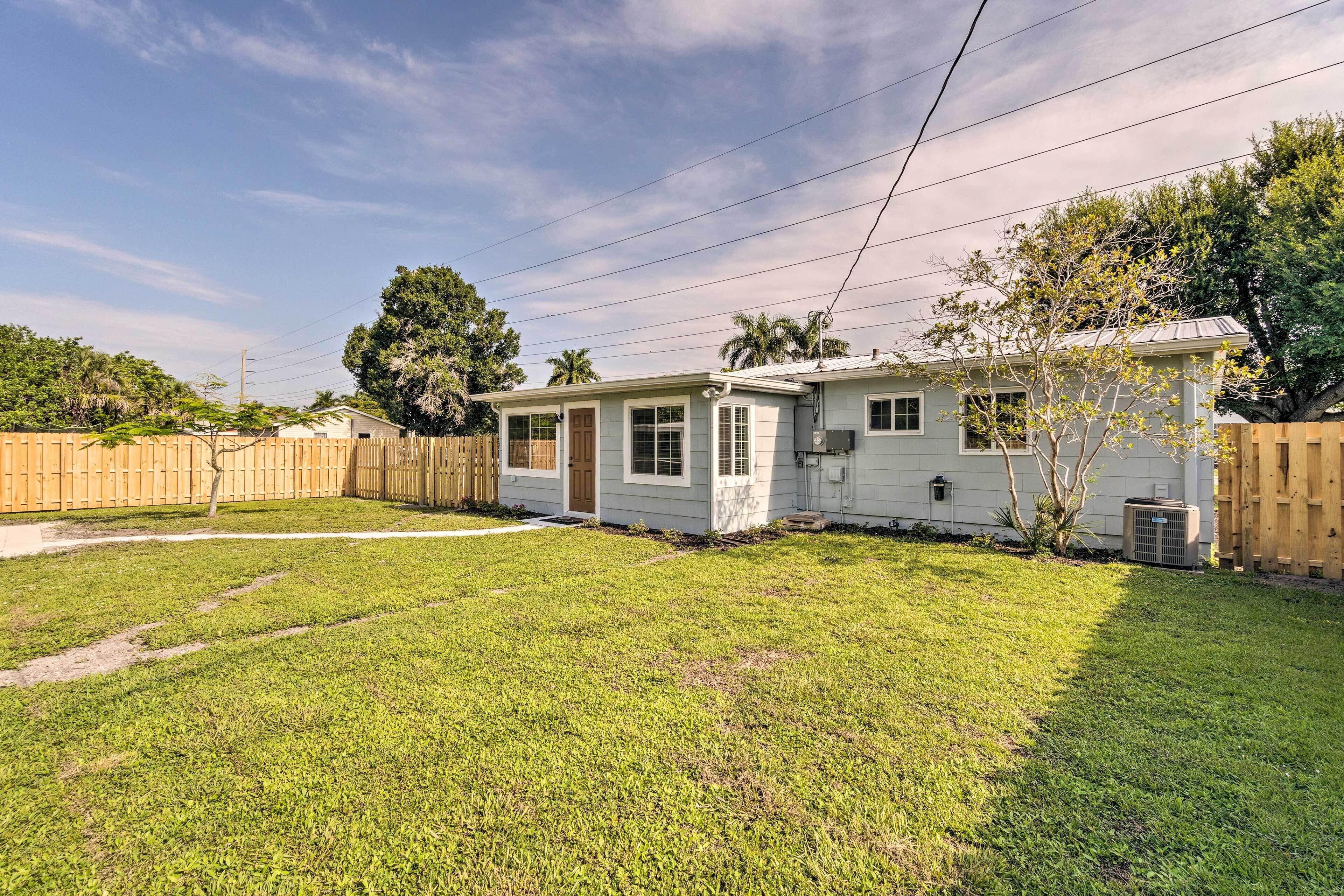 A single-story house with a front door, a small porch, and a fenced backyard.