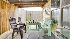 A covered patio area with a wooden table and chairs, a bench, and a glass cabinet. - Pet-friendly PCB Duplex - Walk to Beach! (Panama City Beach)
