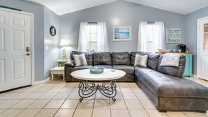A living room with a sectional sofa, a round coffee table, and a ceiling fan. - Pet-friendly PCB Duplex - Walk to Beach! (Panama City Beach)